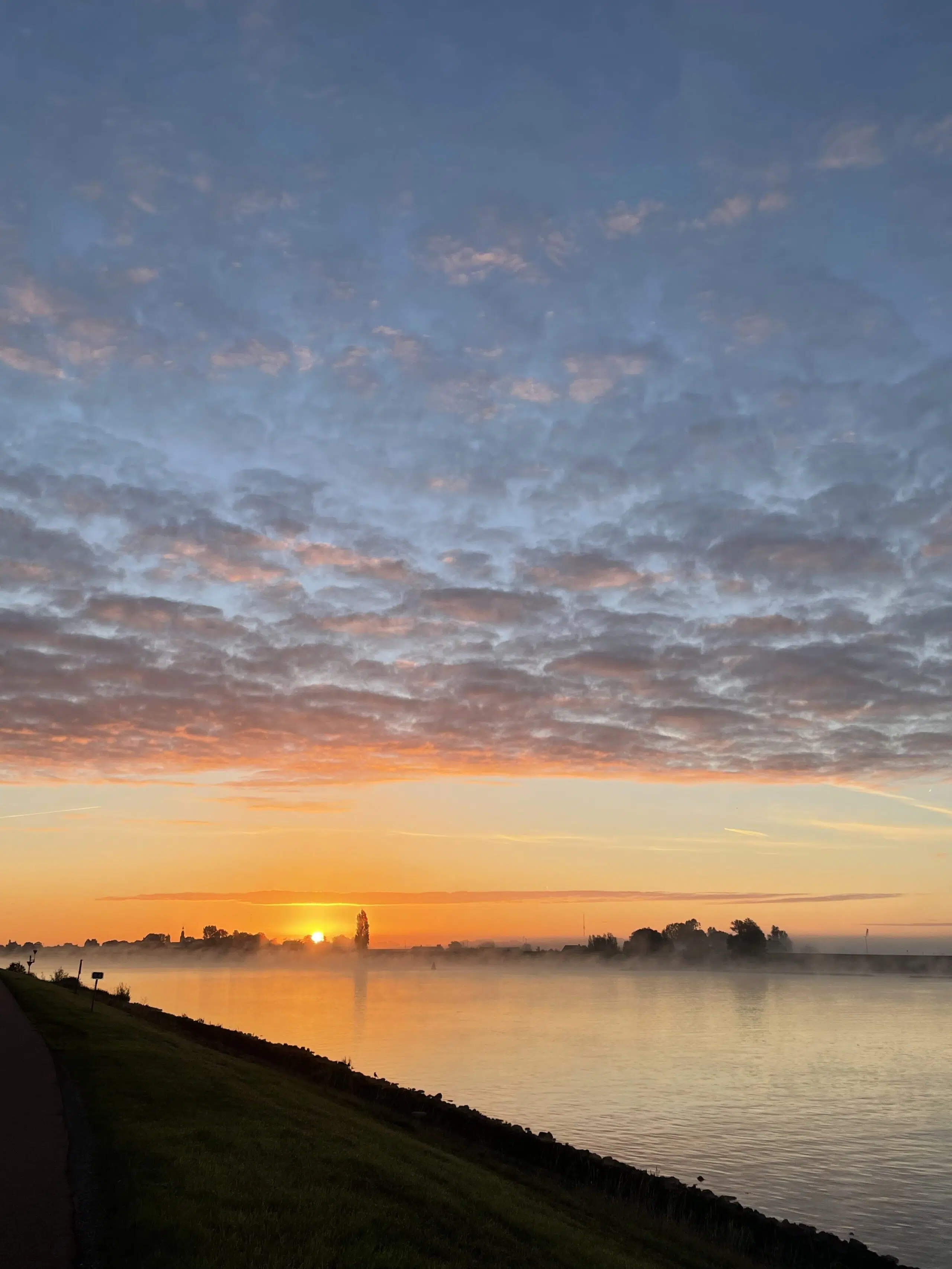 een waterig zonnetje boven een mistige rivier de Lek