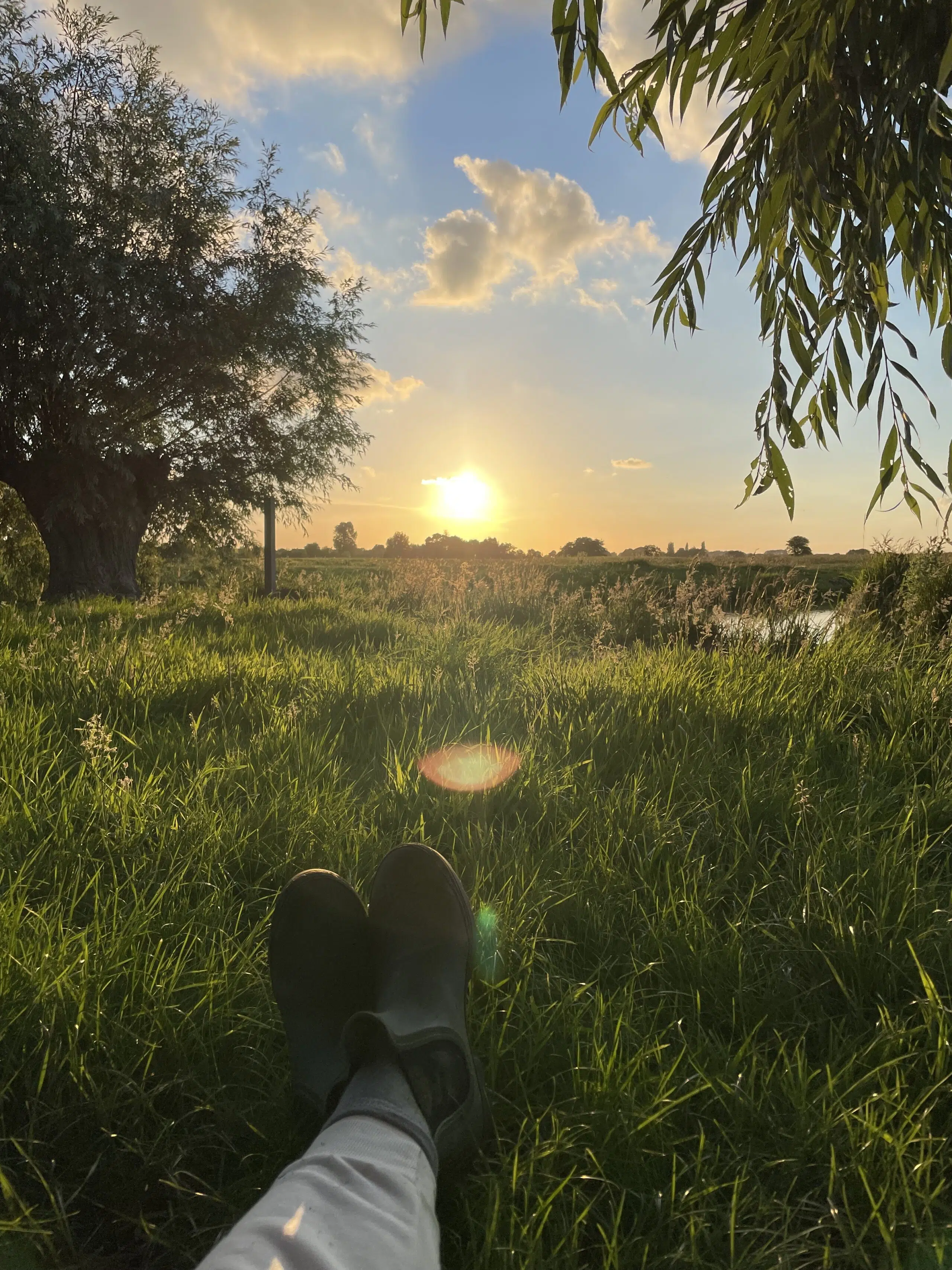 ondergaande zon in het weiland met relaxende groene laarsjes