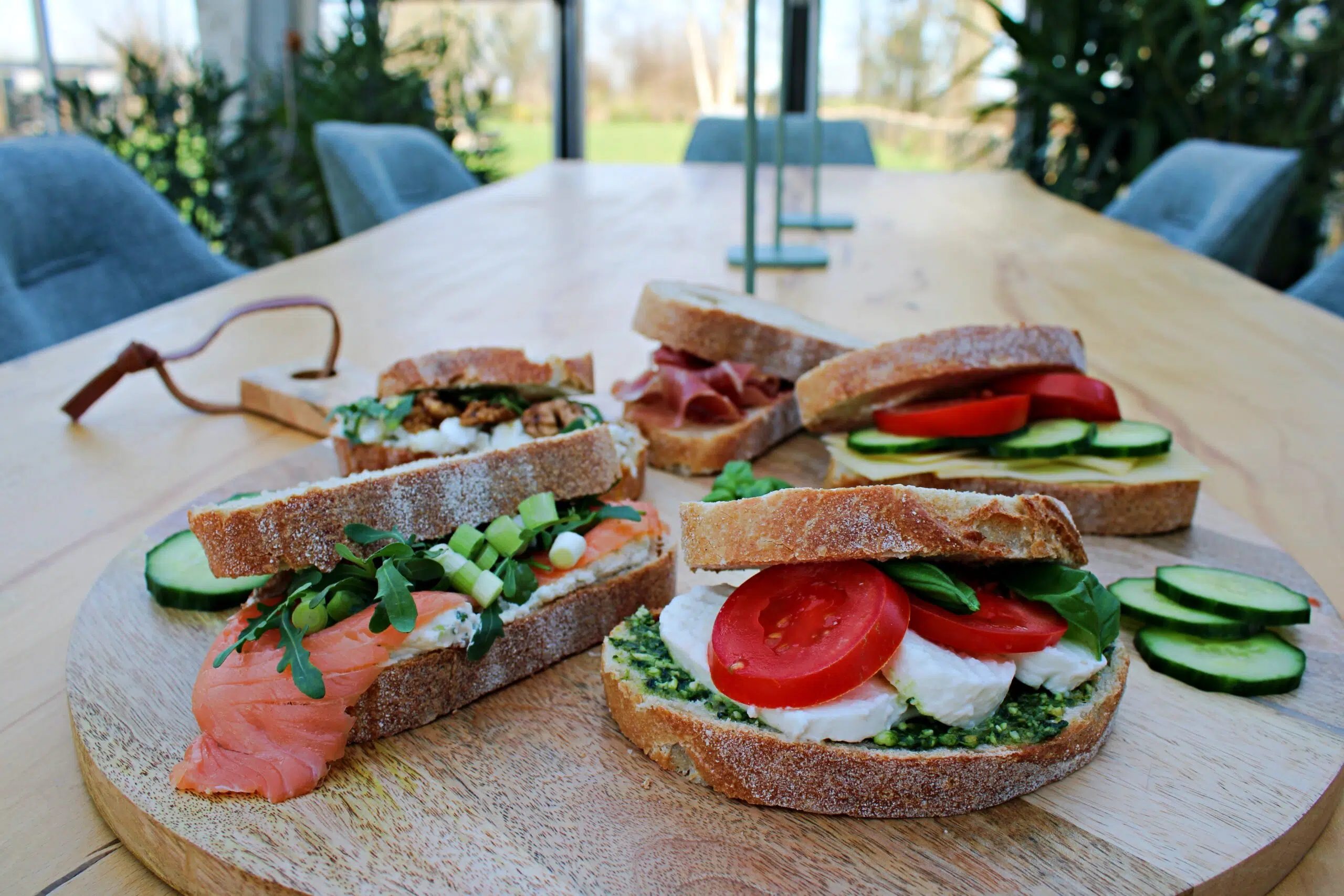 een plank met broodjes op een lange vergadertafel met in de verte het uitzicht in het groen