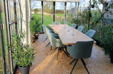 vergadertafel met planten eromheen in een glazen kas met uitzicht op het groen