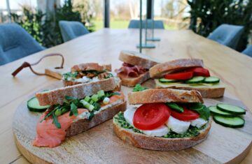 een plank met broodjes op een lange vergadertafel met in de verte het uitzicht in het groen