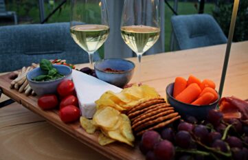 borrelplank met kaasjes, tomaten en andere snacks op een vergadertafel met twee glazen wijn